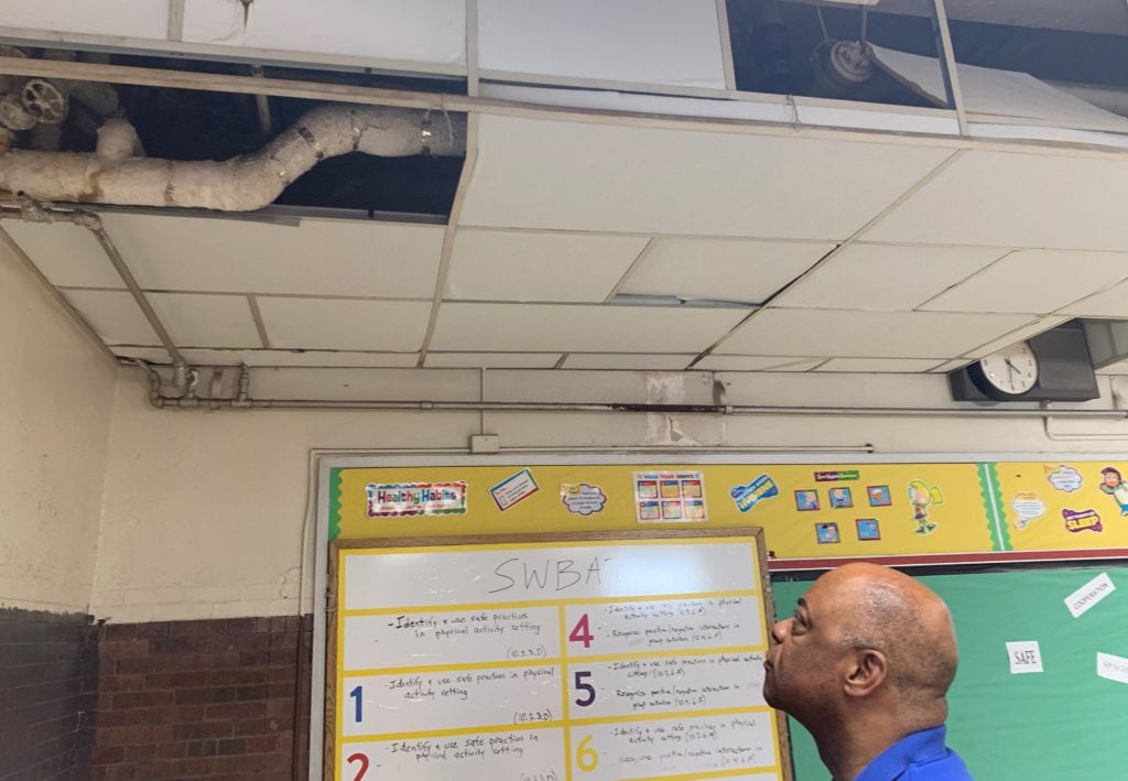 PFT President Jerry Jordan views exposed and damaged asbestos pipe in the school's gym the